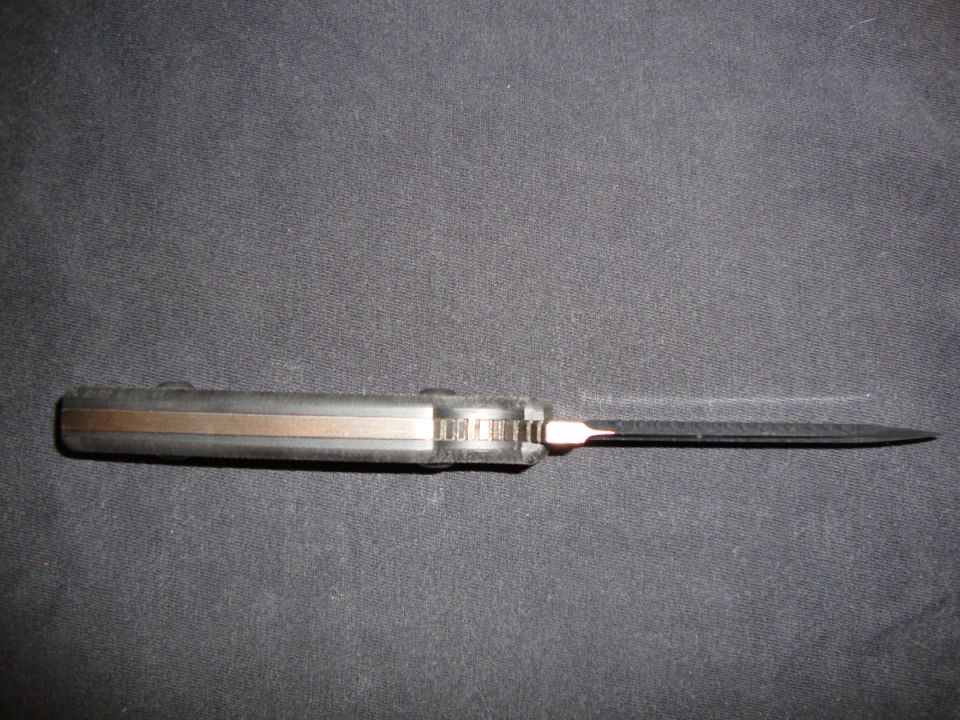 Folding pocket knife with dark blade lying on a gray cloth