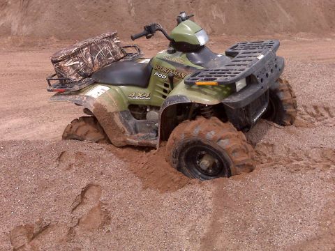 1994 Ford Bronco - This Polaris Sportsman 500 ATV is stuck deep in the mud, with its tires buried and camouflage bag on the rear rack.