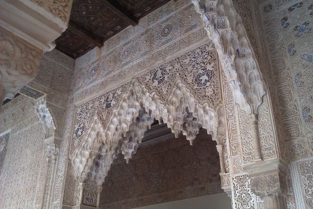 Intricate carvings and arches of an old building, possibly a palace or mosque