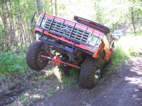1990 Chevrolet Suburban - This heavily modified pickup truck is navigating a challenging off-road trail.