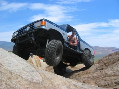 1989 Ford Bronco - This modified truck navigates a rocky incline, its off-road capabilities.