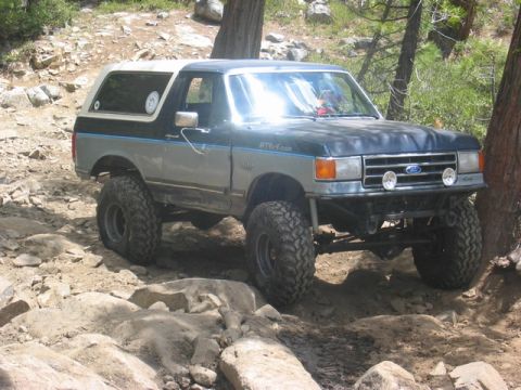 1989 Ford Bronco - Ford Bronco tackles rough terrain on a trail.
