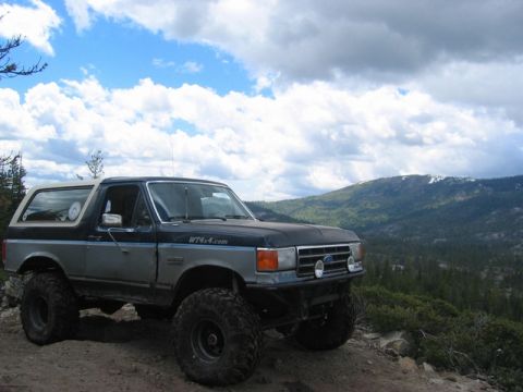 1989 Ford Bronco - Modified 1989 Ford Bronco on a mountain trail under a dramatic sky.