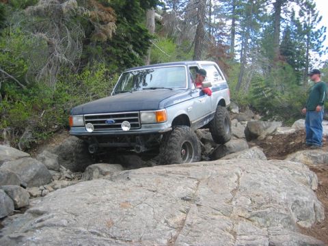 1989 Ford Bronco - A Ford Bronco navigates a rocky trail with a driver and observer present.