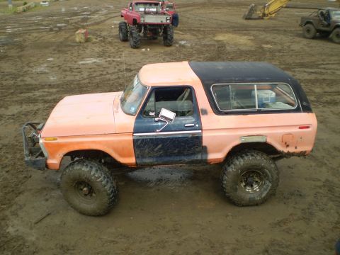 1978 Ford Bronco - A modified 1978 Ford Bronco sits in a muddy off-road area with other vehicles visible in the background.