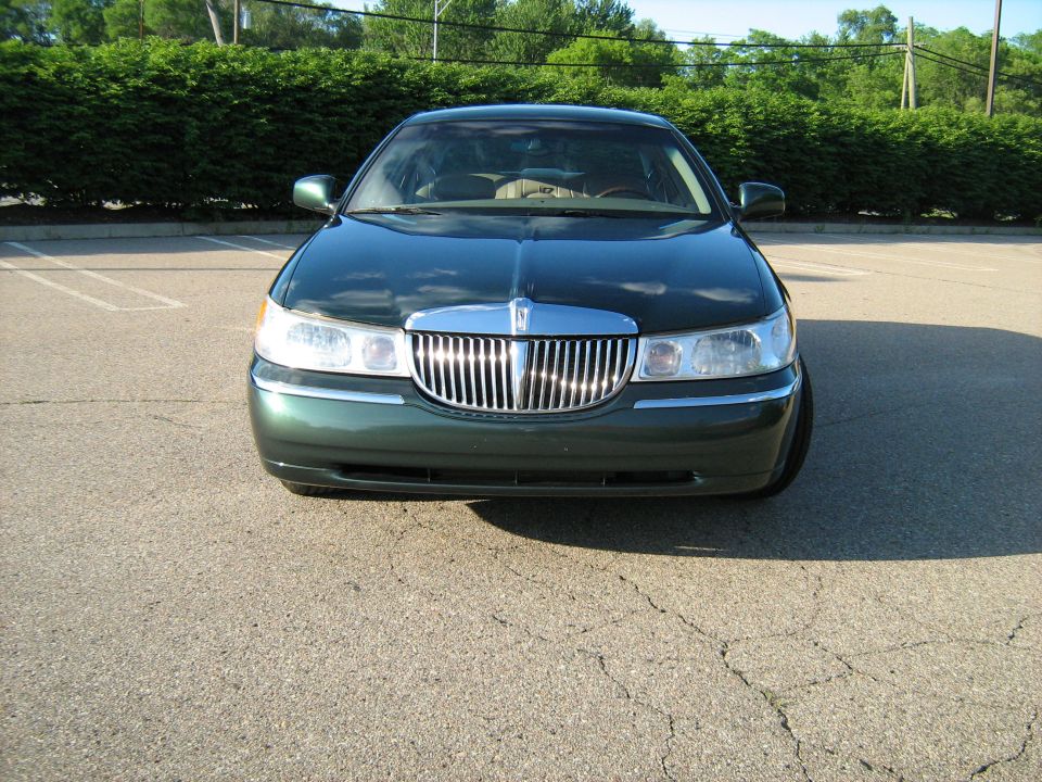 Green sedan front view, chrome grille, parked on asphalt