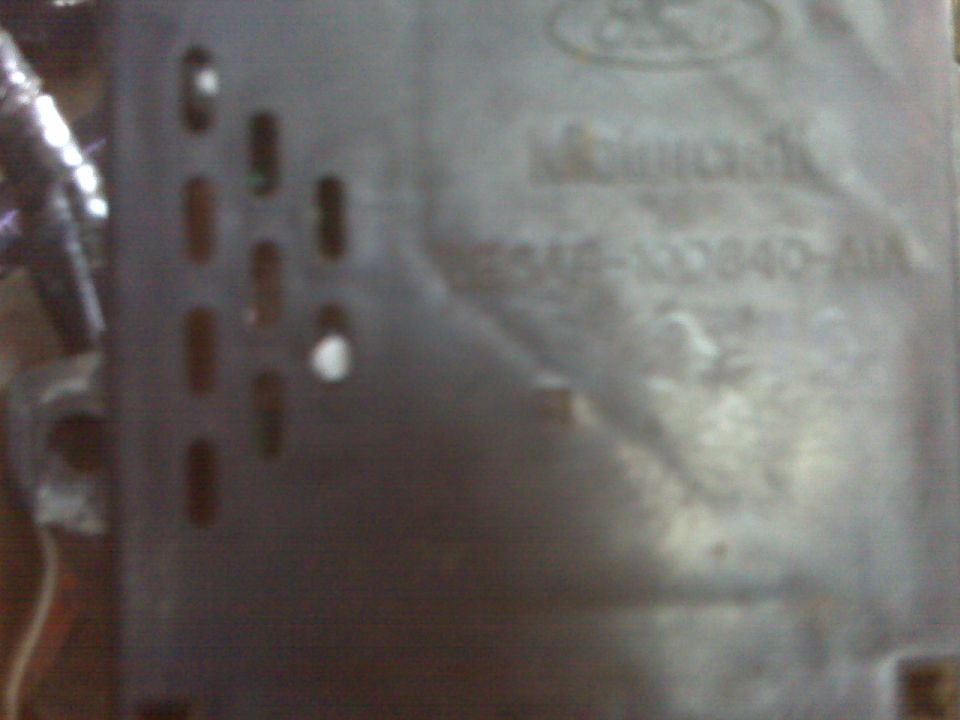Close-up of a metal Ford part with embossed text including 'Manifold' and a part number
