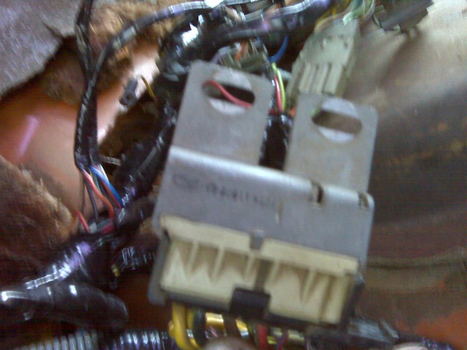 Close-up of a vehicle's interior wiring harness and fuse box with many colorful wires