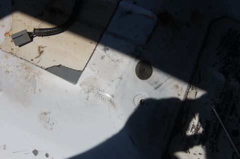 1994 Ford Bronco - Overhead shot of a bare white-painted floor pan or bed panel in harsh sunlight, with a cut-out access opening revealing a gray tank below a…