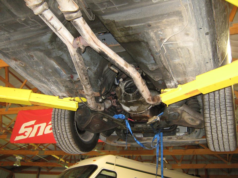 Underside of a car on a lift, showing the exhaust and transmission. A Snap-on banner is visible in the background