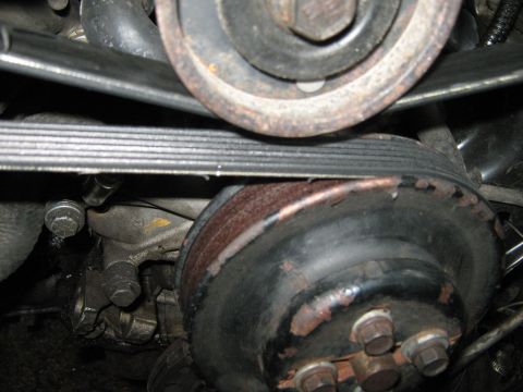 1985 Ford Mustang - Close-up view of engine belts and pulleys, showing signs of wear and rust.