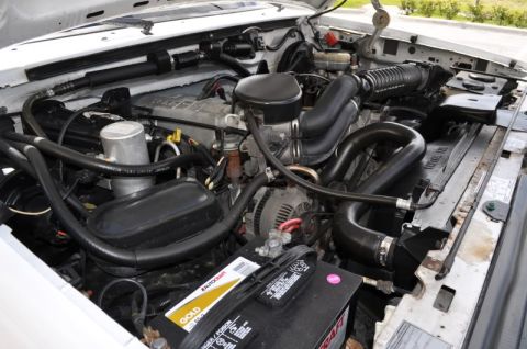 1996 Ford Bronco - Close-up of a Ford V8 engine bay with various hoses and components visible.