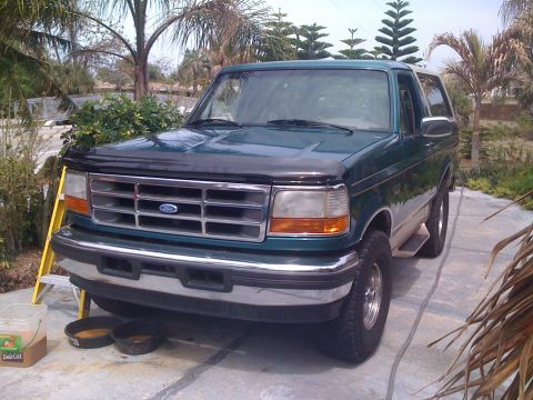 1996 Ford Bronco - Green 1996 Ford Bronco parked outdoors with a ladder and buckets nearby.