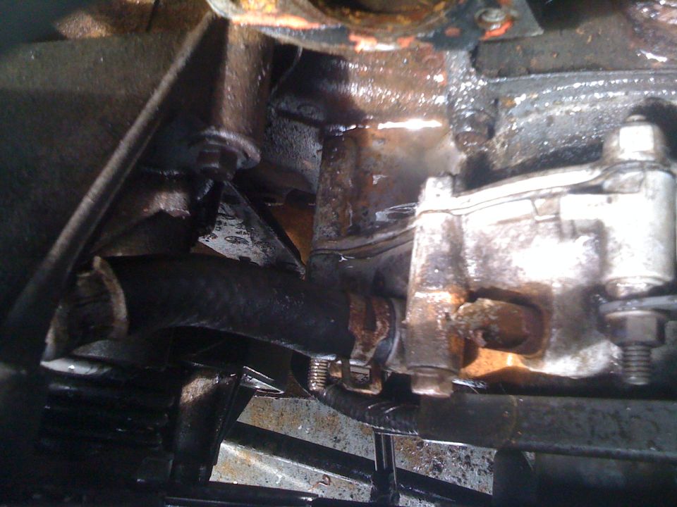 Close-up of a rusty engine component and a black hose with a clamp