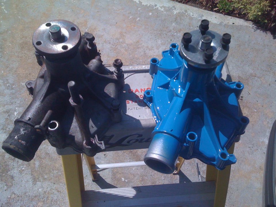 Two car water pumps, one old and rusty, one painted blue, sit on a yellow step stool
