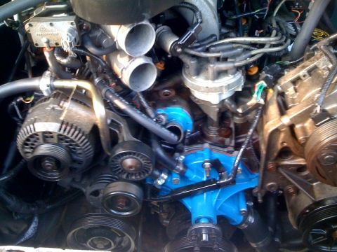 1996 Ford Bronco - Close-up view of an engine bay, highlighting a bright blue water pump and various engine components.