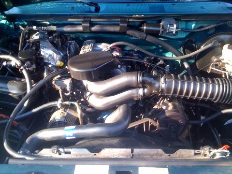 1996 Ford Bronco - The engine compartment of a vehicle is shown, various mechanical components and hoses.