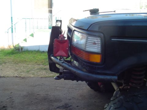1993 Ford Bronco - Front corner of a 1993 Ford Bronco showing the headlight, grille, and custom bumper with a jerry can holder.