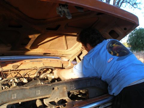 1969 Ford F-250 - A mechanic works on the engine of a vintage truck with the hood open.