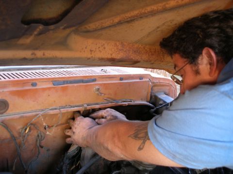 1969 Ford F-250 - A mechanic works on the engine of a vintage truck, with the hood open.