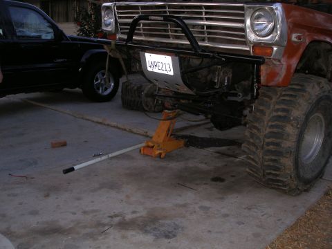 1969 Ford F-250 - Front view of an orange off-road truck being worked on, with a black SUV in the background.