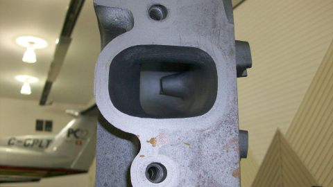1973 Ford Ranchero - A gray metal engine intake manifold is shown in a close-up view, with a port opening visible.