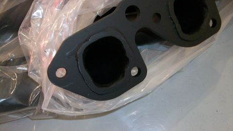 1973 Ford Ranchero - A black exhaust manifold is shown, partially covered in plastic wrap, with a SuperMotors logo in the corner.