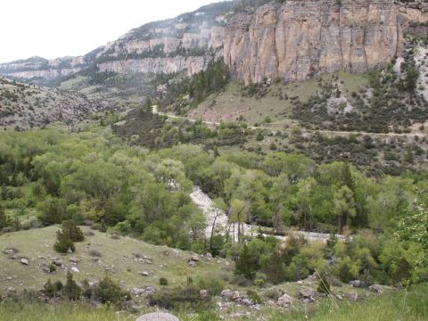2000 Ford F-250 - A scenic view of a mountain valley with a road and river, lush greenery and rocky cliffs.
