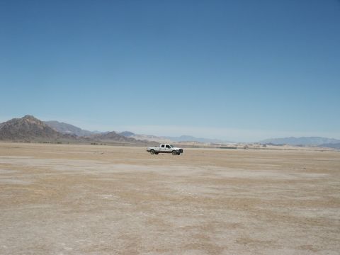 2000 Ford F-250 - A white 2000 Ford F-250 pickup truck is parked in a vast, arid desert landscape with mountains in the distance.
