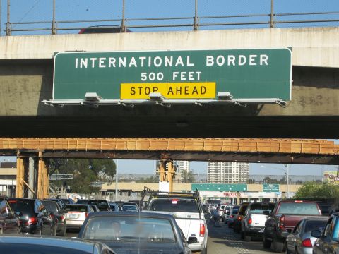 1986 Ford Bronco - Traffic backs up at the international border crossing, with a sign indicating 'STOP AHEAD' 500 feet away.