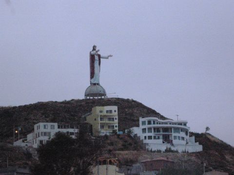 1986 Ford Bronco - A large statue of Christ stands atop a hill, with buildings clustered below. The sky is overcast.