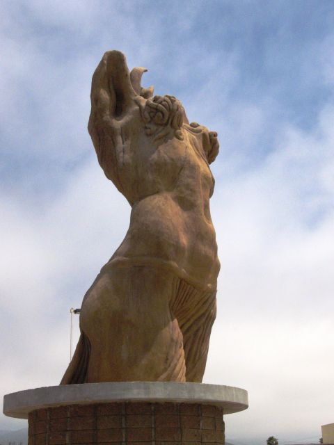 1986 Ford Bronco - A large statue of a figure with its head thrown back stands on a pedestal against a sky with clouds.