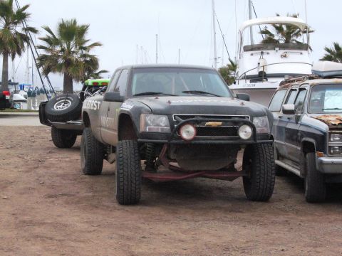 1986 Ford Bronco - A modified Chevrolet pickup truck is parked near boats and other vehicles at a marina.