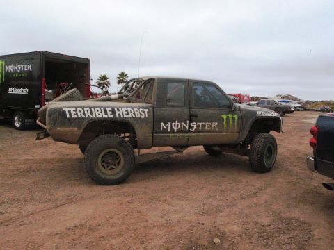 1986 Ford Bronco - This off-road truck, branded with Monster Energy logos and "Terrible Herbst" text, is seen at an event, possibly Baja 500.