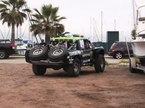 1986 Ford Bronco - A custom off-road truck with sponsor decals is parked in a lot near a marina.
