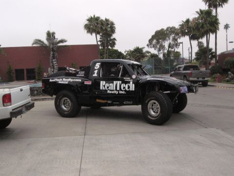 1986 Ford Bronco - This black off-road truck, number 51, displays "RealTech Realty Inc." branding and appears to be a custom build, not a 1986 Ford Bronco.