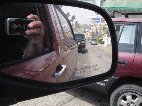1986 Ford Bronco - A red 1986 Ford Bronco with an aftermarket bumper is reflected in the side mirror of another vehicle.