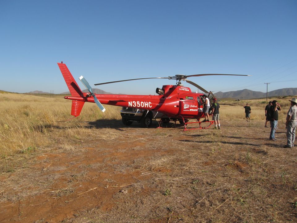 Red helicopter with N350HC on the side, parked in a dry, grassy field