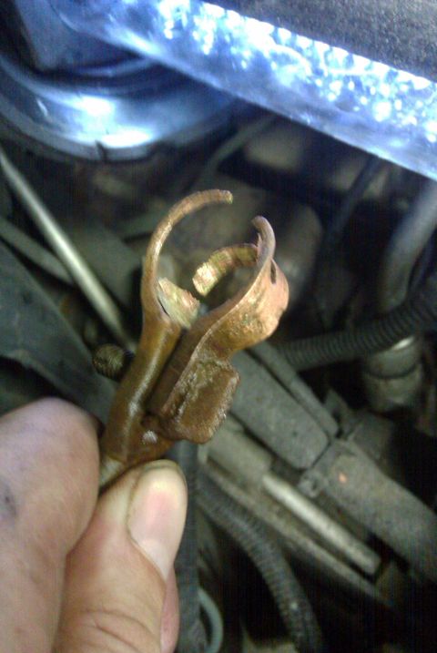 2002 Chrysler 300M - A close-up shows a rusty metal clip being held by a hand, with various engine components visible in the background.