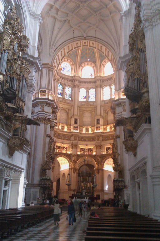 Cathedral interior with pipe organs, stained glass windows, and checkered floor