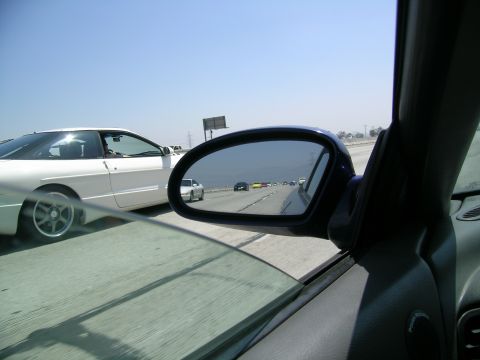 1993 Ford Probe - A white 1993 Ford Probe is seen driving on a highway, with other vehicles visible in the side mirror.