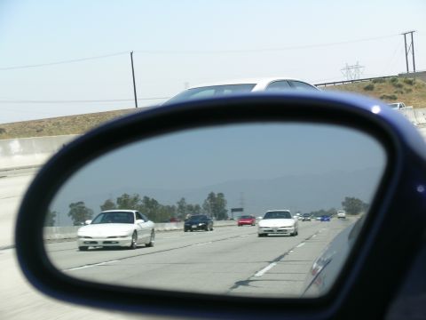 1993 Ford Probe - A white 1993 Ford Probe is visible in the side mirror of another vehicle on the highway.