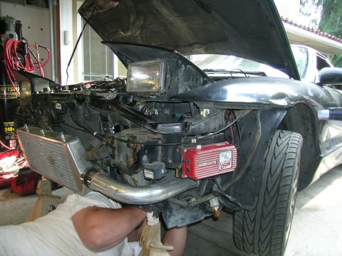 1995 Ford Probe - Front end of a car undergoing modifications, with engine components exposed and a person working on it.