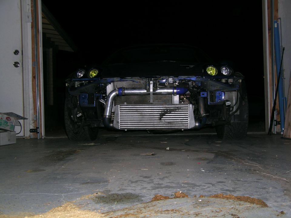Front of car with exposed intercooler and turbo piping, yellow headlights