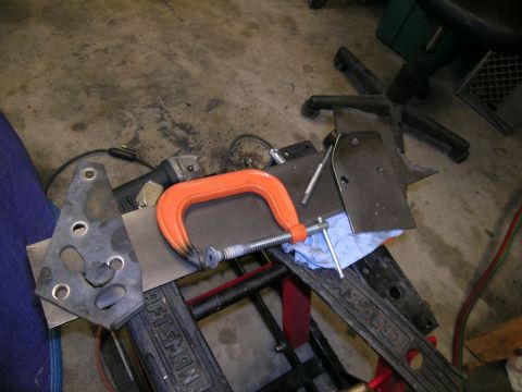 1995 Ford Probe - Metal fabrication in progress with a C-clamp, angle grinder, and various metal parts on a workbench.
