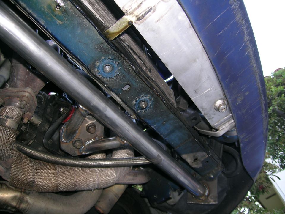 Close-up of custom exhaust piping and engine components in a car's engine bay