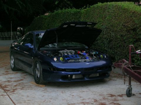 1995 Ford Probe - The front of a blue 1995 Ford Probe is visible with its hood raised, revealing engine components and aftermarket intercoolers.