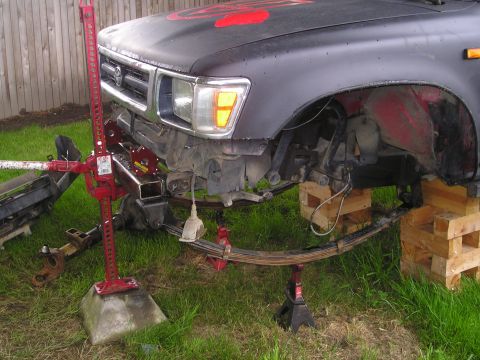 1990 Toyota Pickup/SR5 - Front suspension of a Toyota truck is elevated for maintenance, revealing its leaf spring system.