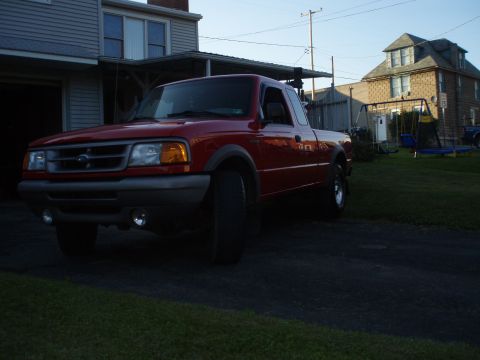 1997 Ford Ranger - A red pickup truck is parked in a driveway next to a house.