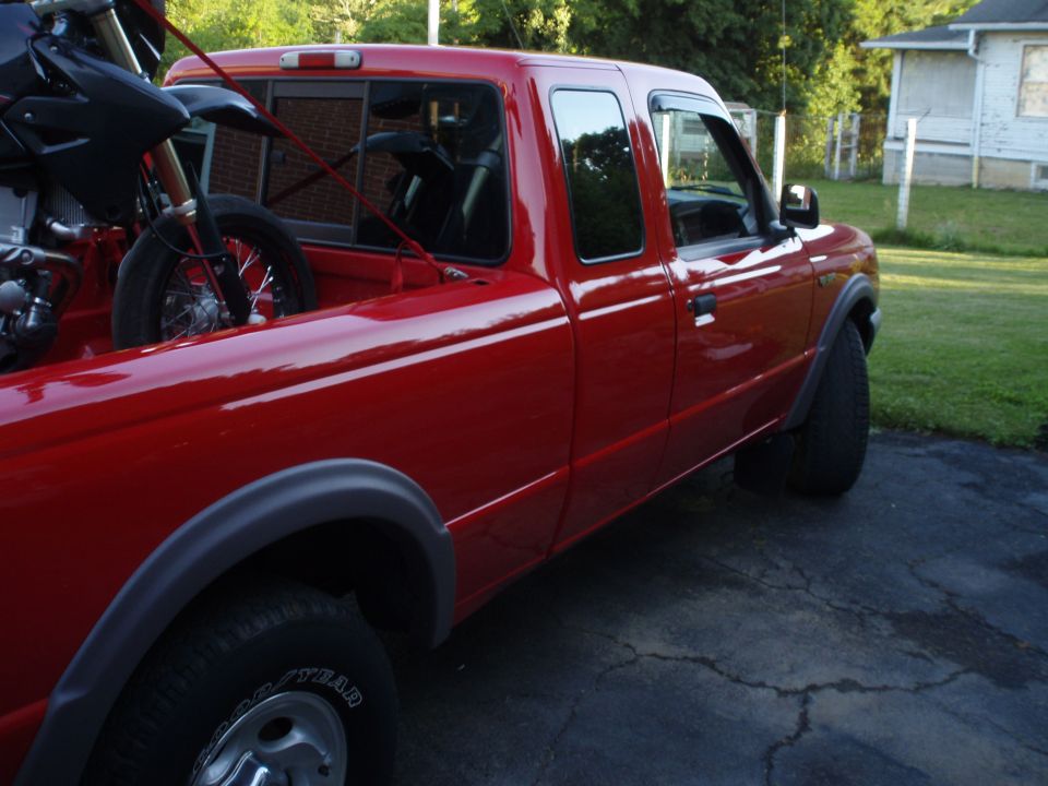 1997 Ford Ranger pickup truck, red, with a dirt bike loaded in the bed